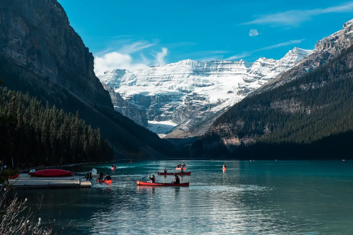 Red canoes on the turquoise water of Lake Louise below Victoria Glacier