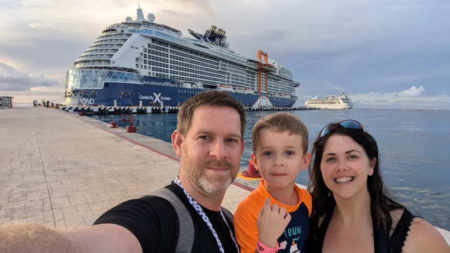 A family at the pier with their cruise ship behind them