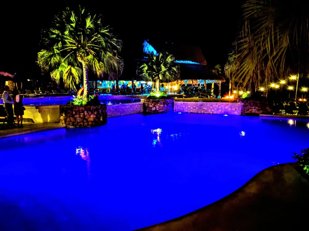 A palm-lined resort pool lit blue at night in Costa Rica