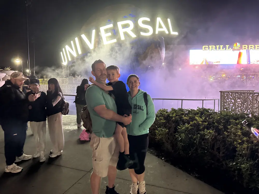 Travelers in front of the lit Universal Studios globe at night