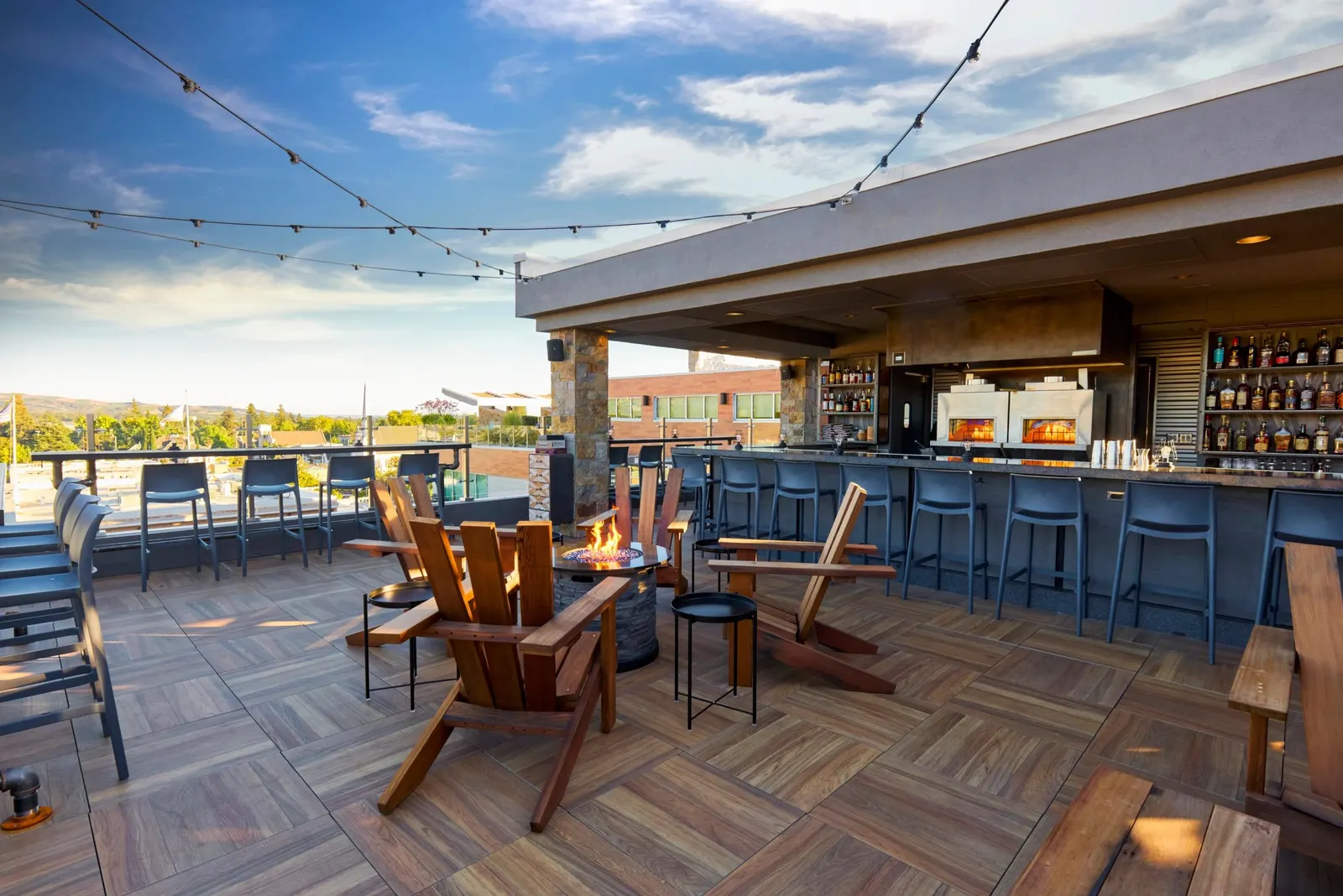 A rooftop lounge with a firepit at dusk