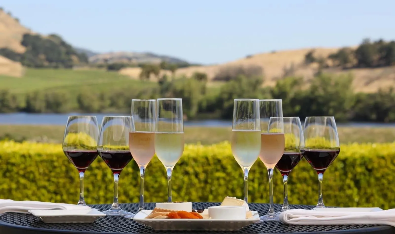 A flight of three wine glasses against rolling vineyards