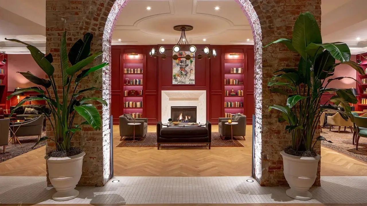 A warm hotel lobby with a lit fireplace and soft lounge seating