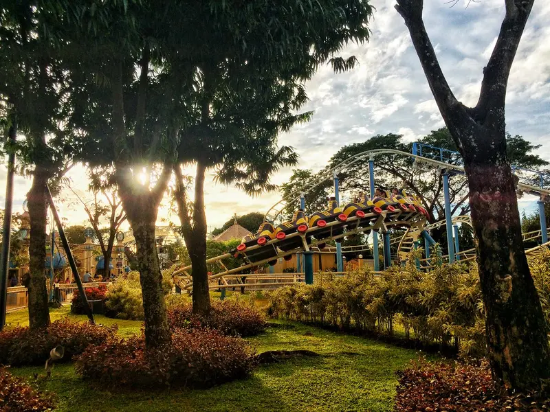 A roller coaster winding through a sunny amusement park